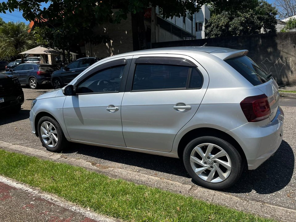 Vista lateral em três quartos do Volkswagen Gol prata anunciado, estacionado na rua