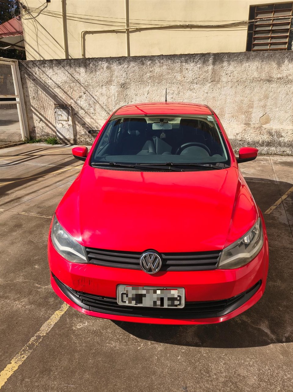 Vista frontal do Volkswagen Gol vermelho anunciado em estacionamento externo