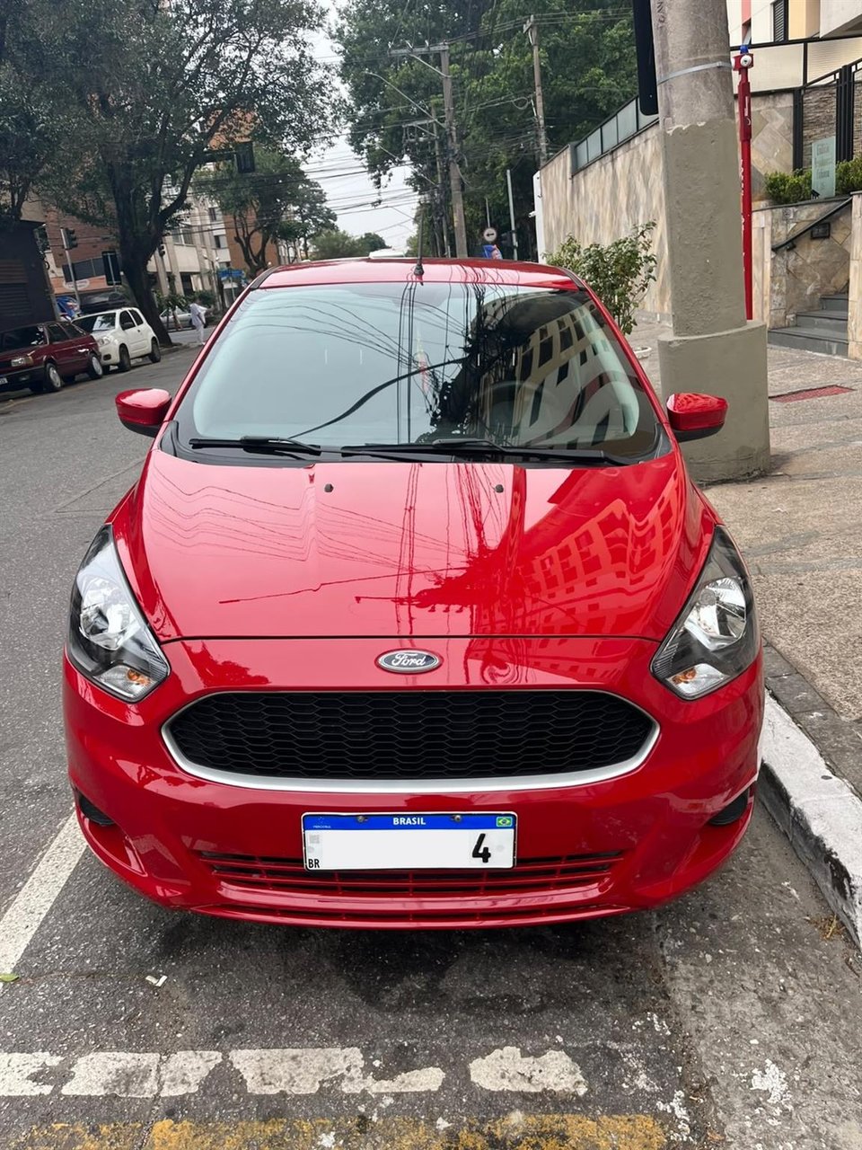 Vista frontal do Ford Ka vermelho anunciado, estacionado na rua