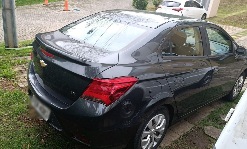 Vista traseira em três quartos do Chevrolet Prisma cinza anunciado em área externa